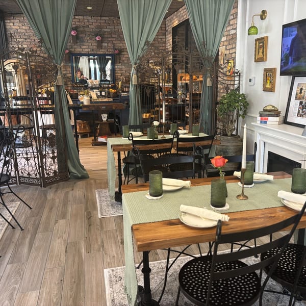 Dining room at Maldon's Brasserie with set tables, brick walls, and decorative metal screens.