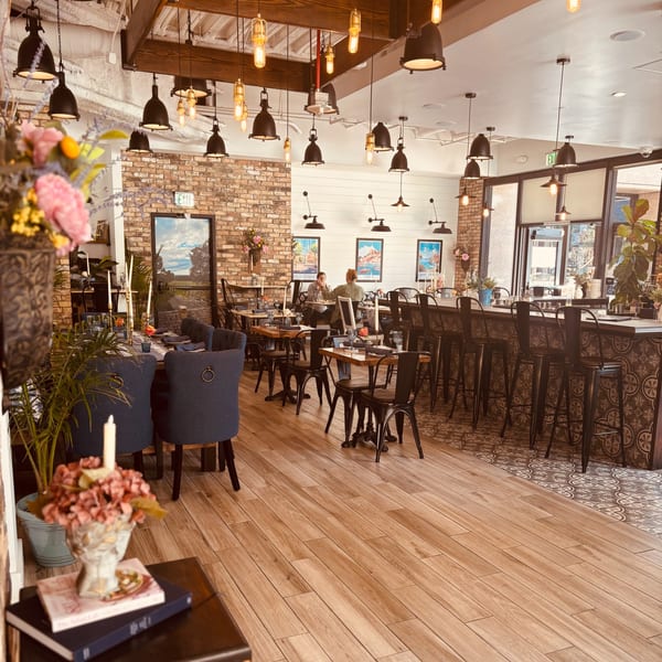 Maldon's Brasserie dining room with brick walls, wooden floors, and a bar area, featuring patrons dining.